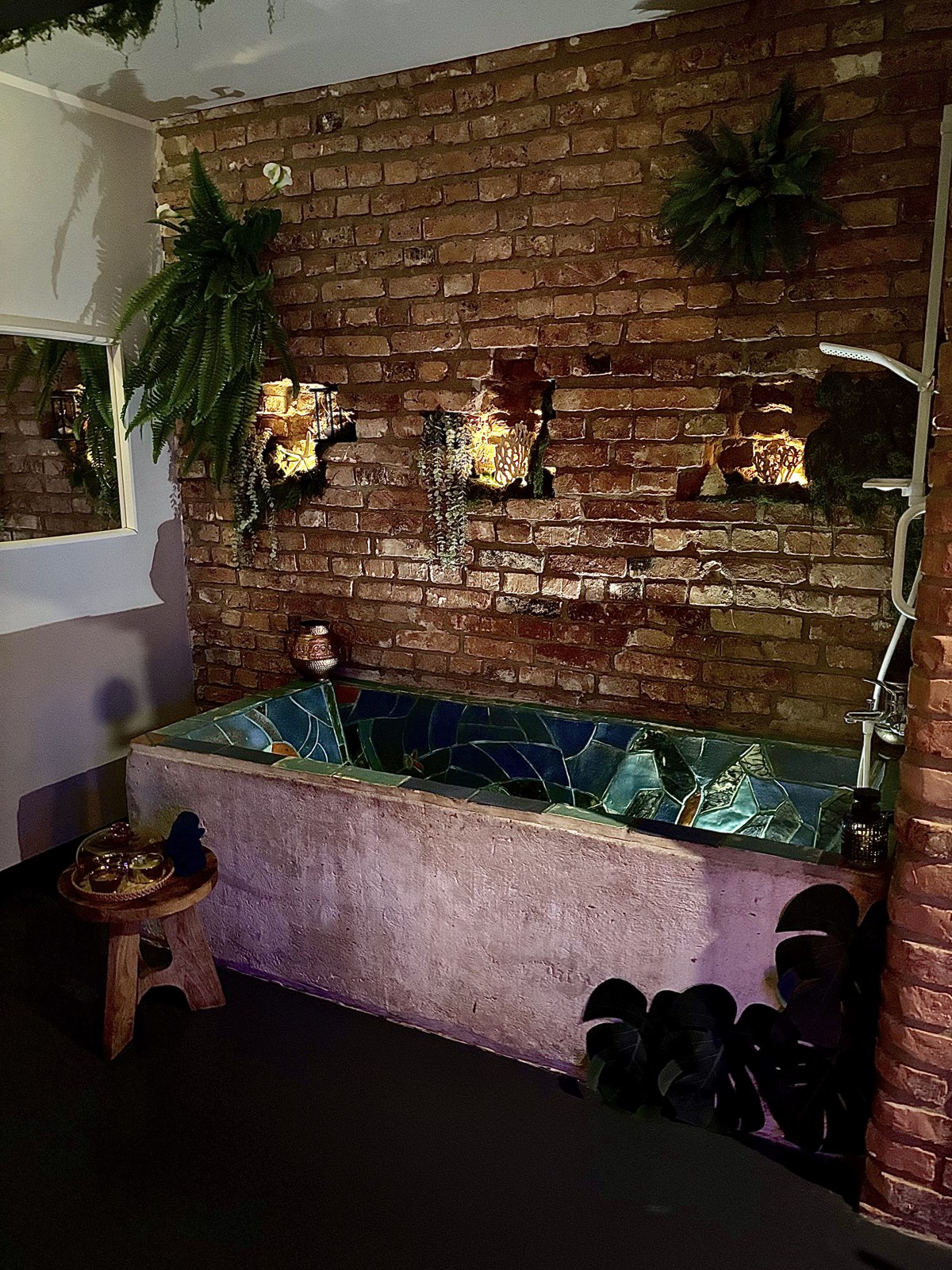 Mosaic-tiled bathtub built into an exposed brick wall — Property Presentation Reset, Poznań apartment