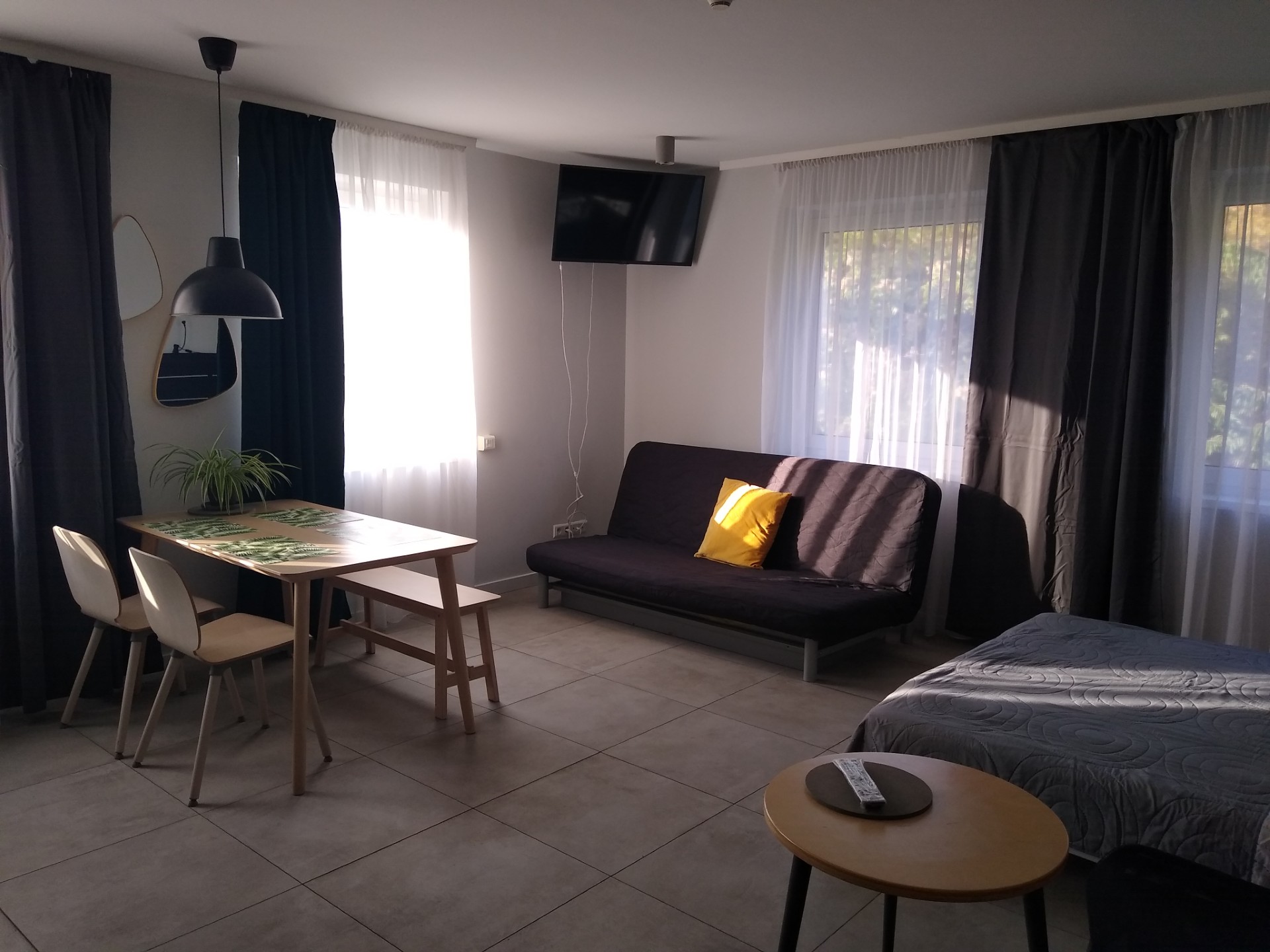 Studio apartment dining table and sofa area with wall-mounted TV — Property Presentation Reset, Poznań apartment listing