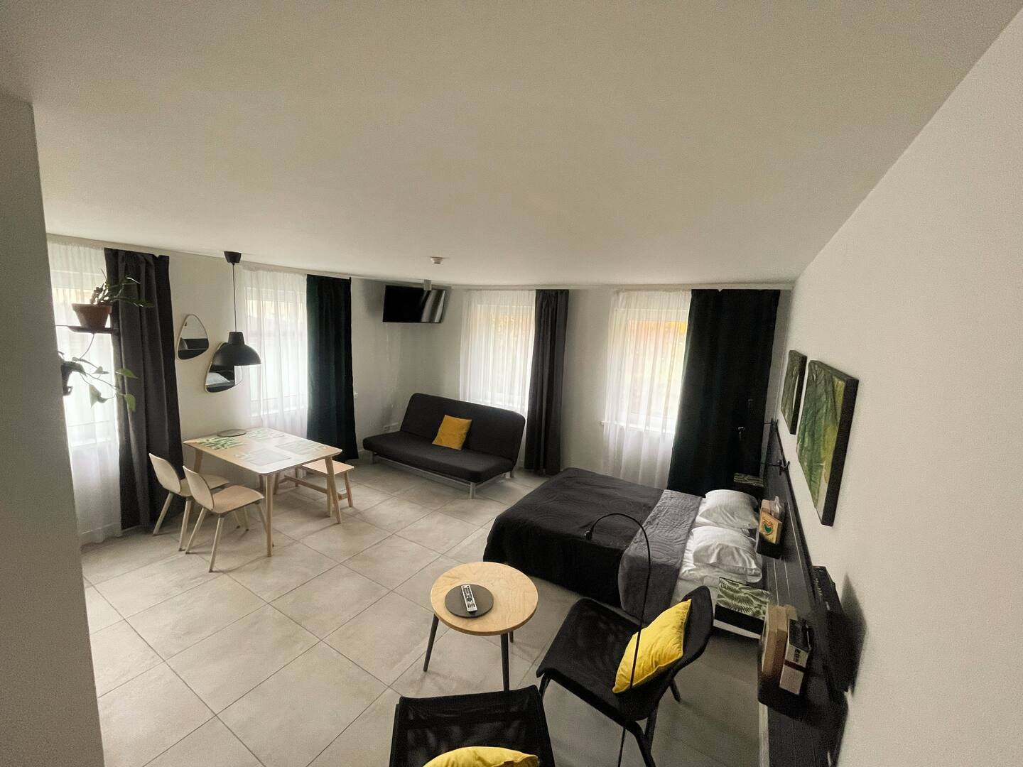 Wide view of the styled studio apartment with dining table, bed and seating — Property Presentation Reset, Poznań apartment listing